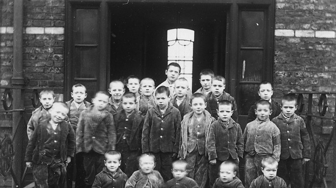 A group of children pose outside a 19th century group home