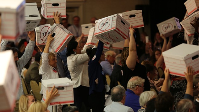 Democratic delegates raise cardboard boxes meant to represent hundreds of thousands of signatures against the Trans-Pacific Partnership.