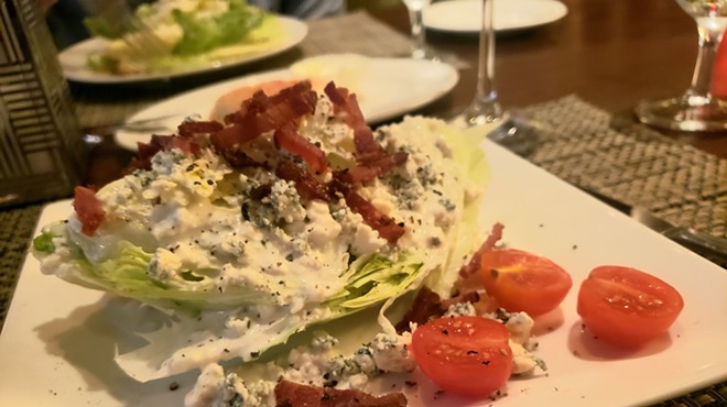 Classic wedge salad topped with bacon lardons and Danish blue cheese.