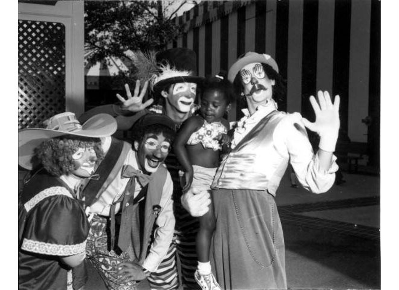 Clowns holding a young girl