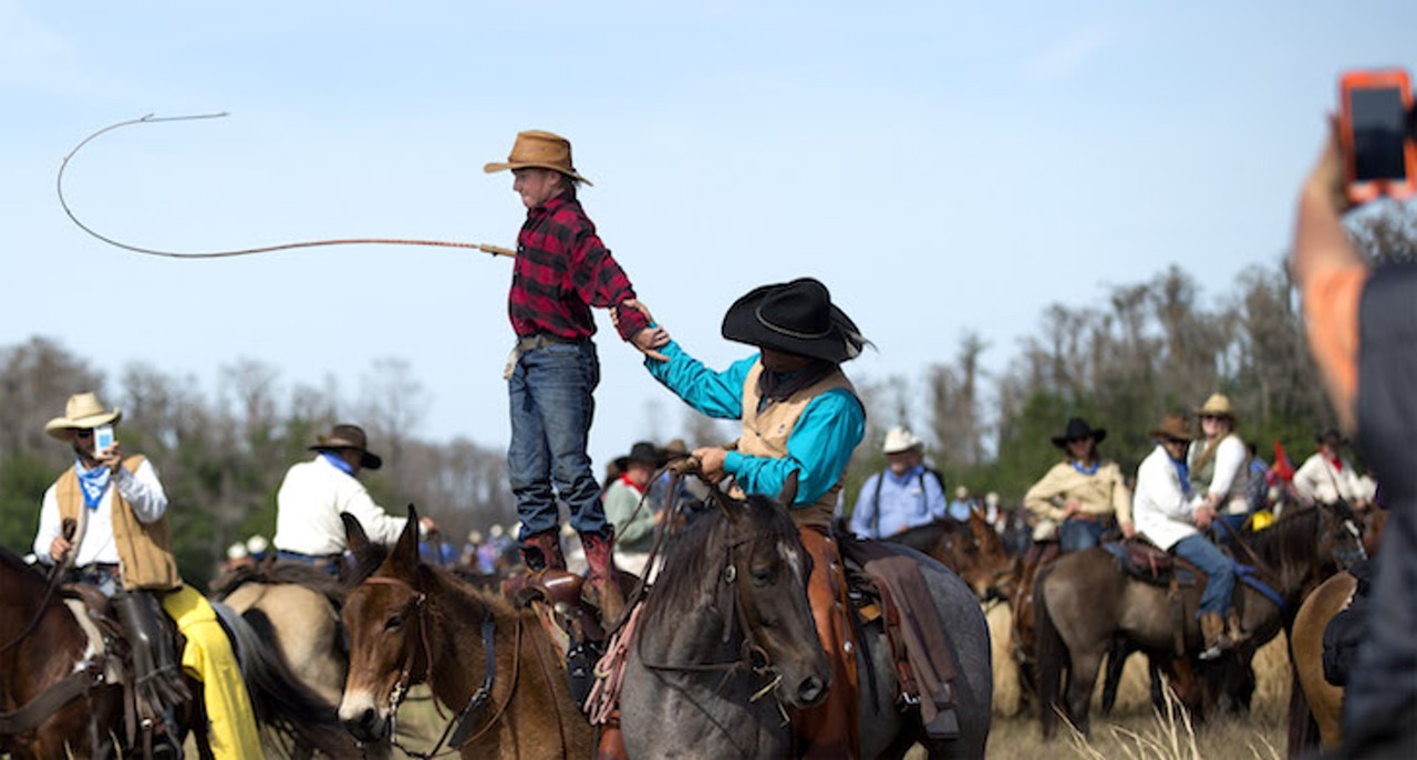 While having his photograph taken, Justin Mickelsen, 13, stands atop his horse and cracks his whip at the end of the Great Florida Cattle Drive '16. "Awesome." said Mickelsen of Mobile, Alabama about his six day trip into the Florida wilderness.