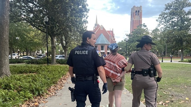 An unidentified University of Florida police officer and Florida Highway Patrol trooper walk a handcuffed protester away from the site on the university's campus where law enforcement arrested nine pro-Palestinian protesters late Monday, April 29, 2024. They were among the first such arrests on campuses in Florida.