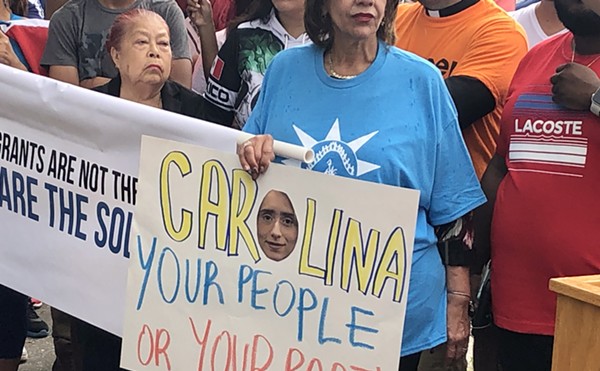 An immigration rights advocate holds a sign protesting Florida Rep. Carolina Amesty's support for a sweeping immigration bill that worries rights advocates.