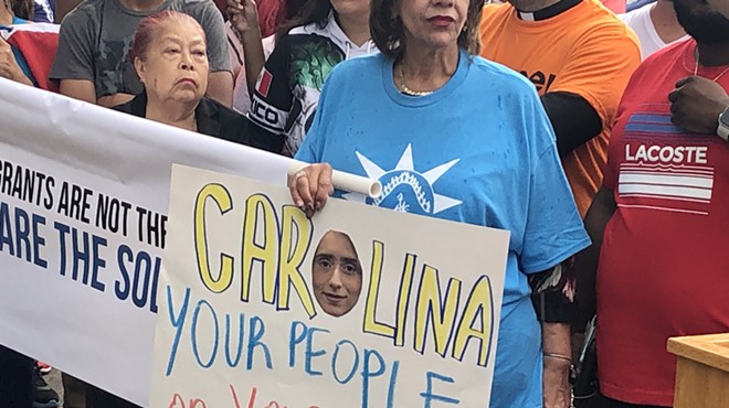 An immigration rights advocate holds a sign protesting Florida Rep. Carolina Amesty's support for a sweeping immigration bill that worries rights advocates.