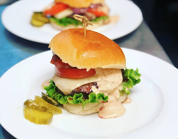 A duck-fat infused beef burger with caramelized onions and Raclette cheese on a brioche bun. - Photo via Bites & Bubbles/Instagram