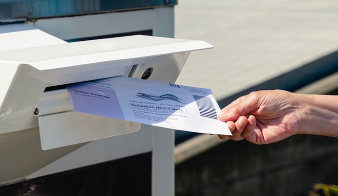 Putting a vote-by-mail ballot in the postbox. - ADOBE