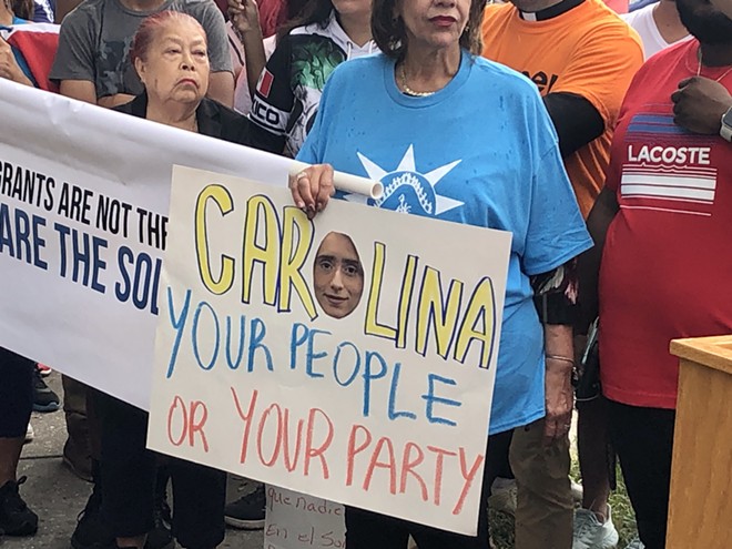 An immigration rights advocate holds a sign protesting Florida Rep. Carolina Amesty's support for a sweeping immigration bill that worries rights advocates. - McKenna Schueler