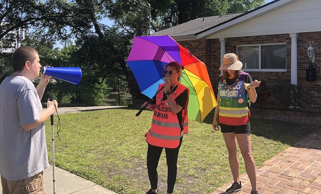 An anti-abortion activist shouts into a bullhorn in the direction of an Orlando abortion clinic, while clinic escorts try to drown out the noise. (May 1, 2024) - Photo by McKenna Schueler