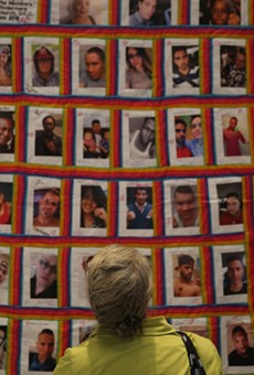 A woman stares at a quilt with the faces of the 49 victims of the Pulse shooting.