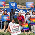 Protesters hold signs in front of the Walt Disney World resort.